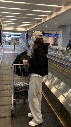 a woman with headphones standing in front of an empty shopping cart at the airport