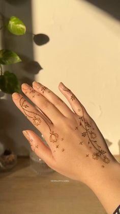 a woman's hand with tattoos on it and a potted plant in the background