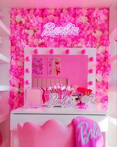 a room with pink flowers on the walls and decorations in front of a mirror that says barbie