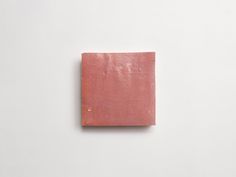 a square piece of pink clay sitting on top of a white surface