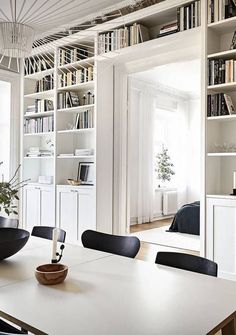 a dining room table with black chairs and bookshelves