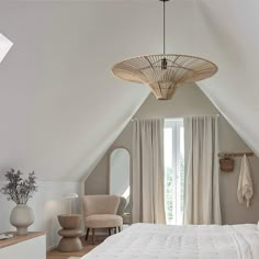 an attic bedroom with white walls and wood flooring is furnished with neutral colored furniture