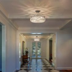 a hallway with a chandelier and checkered flooring on the side walk