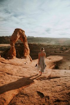 a woman standing on top of a large rock formation in the middle of a desert