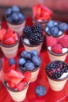 small cups filled with ice cream, berries and blueberries on a red platter