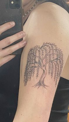 a woman's arm with a tree tattoo on it and a cell phone in her hand