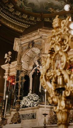 a statue in the middle of a room with chandelier and flowers on it