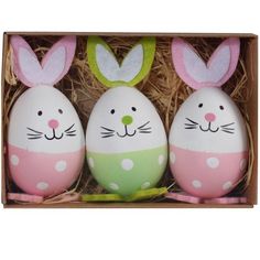 three decorated eggs in a box with bunny ears