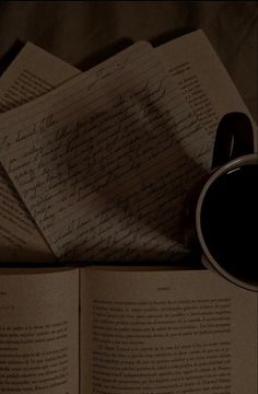 an open book with writing on it next to a cup of coffee