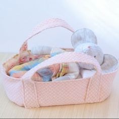 a stuffed animal in a pink basket on top of a wooden table next to a white wall