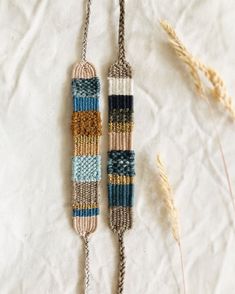 two macrame necklaces are hanging on a white surface next to some dried grass