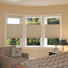 a bed room with a neatly made bed and two windows that have shades on them