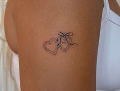 a woman with a tattoo on her arm that has two hearts and a bow in it