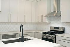 a white kitchen with stainless steel appliances and marble counter tops is pictured in this image