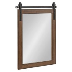 a mirror hanging on the wall with metal bars and a wooden frame in front of it