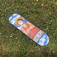 a skateboard laying in the grass with a painting on it's bottom half