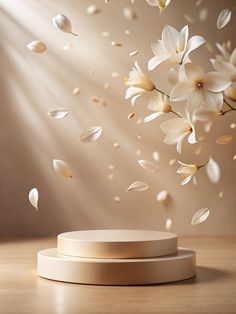 white flowers are falling from the ceiling in front of a light brown background with sunlight streaming through it