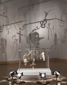 an exhibit with various objects on display in front of a shadow projected wall behind it