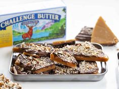 several pieces of chocolate and nuts in a metal tray next to a box of butter