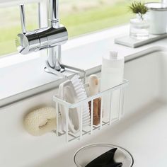 a kitchen sink with soap, toothbrushes and other bathroom items in it next to a window