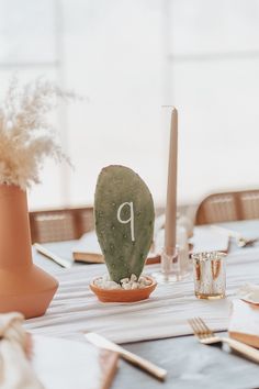 the table is set for a wedding reception with cactus decorations and place settings on it