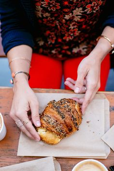 a woman is holding a piece of bread in her hand while sitting at a table