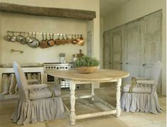 a table and chairs in a room with pots on the wall above it, hanging pans