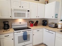 a kitchen with white cabinets and appliances