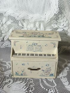 an old white piano sitting on top of a lace tablecloth covered bed sheet next to a window