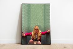 a woman sitting on the floor in front of a green wall with her hands out