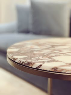 a marble table top sitting in front of a couch with pillows on the back ground