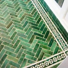 a bathroom with green and white tiles on the floor