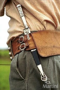 a close up of a person wearing a leather belt with a knife in his pocket