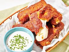 a basket filled with fried food next to a bowl of ranch dressing