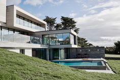 a house with a swimming pool in front of it on top of a grassy hill