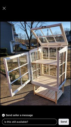 a wooden shelf with glass doors on the top and bottom shelves, in front of a house