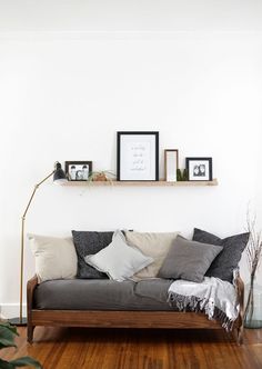 a couch sitting on top of a hard wood floor next to a wooden shelf filled with pictures