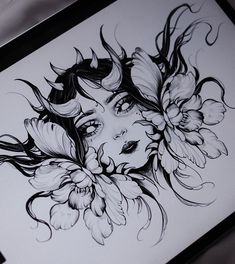 a drawing of a woman's face with flowers in her hair is displayed on a table