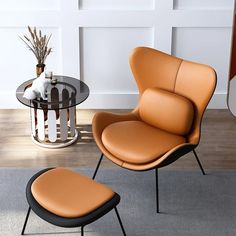 an orange leather chair and footstool in front of a glass table with vases on it