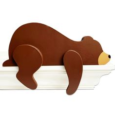 a brown bear laying on top of a white shelf