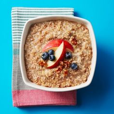 a bowl of oatmeal topped with an apple and blueberries on top