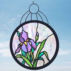 a stained glass window hanging from the side of a building with purple flowers in it