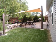 an outdoor patio with tables and chairs in the back yard, next to a large lawn