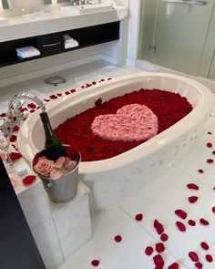 a bathtub filled with rose petals and a bottle of wine in the middle of it