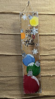 a wooden sign that says deck the hallo with ornaments hanging from it's sides