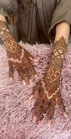 a woman's hands with hennap on it sitting on a pink rug