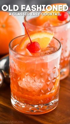 two glasses filled with old fashioned cocktails on top of a wooden table next to oranges