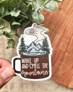 someone holding up a sticker that says wake up and smell the mountains