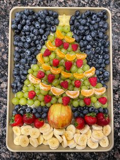 A colorful christmas tree shaped fruit platter on a silver baking tray. A star fruit slice forms the star on top of the tree, and mandarin oranges are strung together like streamers going around the tree. Cute Christmas Fruit Trays, Fruit Plate Christmas, Fruits Christmas Tree, Christmas Theme Fruit Tray, Fruit Christmas Board, Easy Christmas Fruit Tray, Santa Fruit Platter, Christmas Party Fruit Tray Ideas, Christmas Fruit Platter Holiday Parties