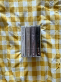 three cassettes sitting on top of a yellow and white checkered table cloth,